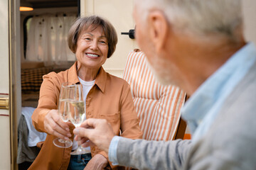 Senior active couple spouses clinking cheering toasting wine glasses while traveling driving camper...
