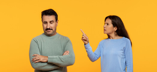 A man with a skeptical expression crosses his arms while a woman points a finger upwards