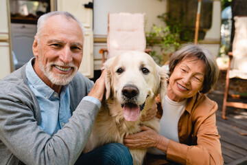 Portrait of happy old senior couple family wife and husband with dog golden retriever, playing and...