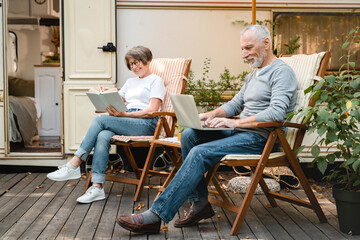 Remote workers, freelance concept. Caucasian senior old grandparents couple relaxing near trailer...