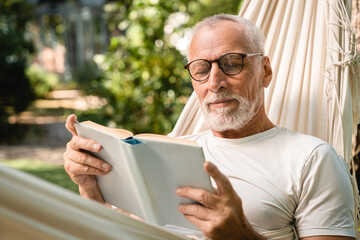 Concentrated dreamy old senior elderly caucasian grandfather man relaxing resting in hammock while...