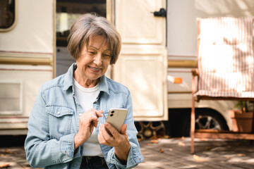 Cheerful caucasian senior old elderly grandmother businesswoman freelancer using cellphone smart...