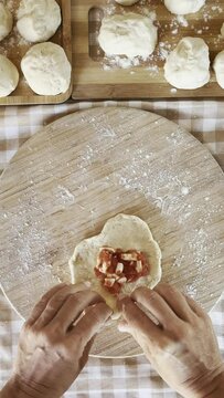 Woman in colorful apron prepares traditional stuffed food. This is a step-by-step recipe for cooking dough, panzerotti and baked or pastry products. Handmade concept​