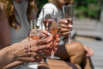 girls sit and hold glasses of champagne in the hands with stickers at the party