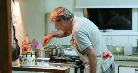 Candid older man cooking at the kitchen in the evening