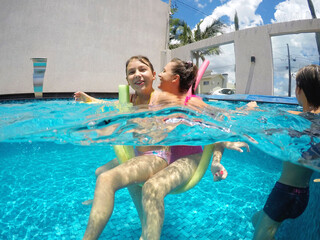 mãe brincando com filha em água de piscina, férias de verão 