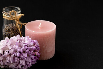 Aromatherapy concept, spa concept, blooming hyacinth flower, dry aromatic herbs in a glass bottle, candle on dark background, copy space right.