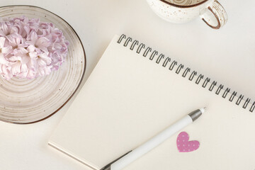 Blank sketchbook with a pink heart, a cup, a plate with a blooming flower, a pen on white background, Love letter, Valentine’s Day concept