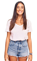 Young hispanic woman wearing casual white tshirt with a happy and cool smile on face. lucky person.