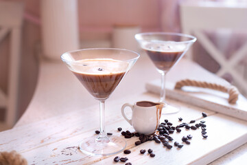 Espresso Martini cocktail in a martini glass decorated with coffee beans and a small jug with...