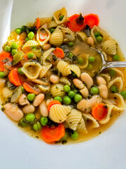 Close up from above from home made winter soup with pasta, beans, peas and carrot