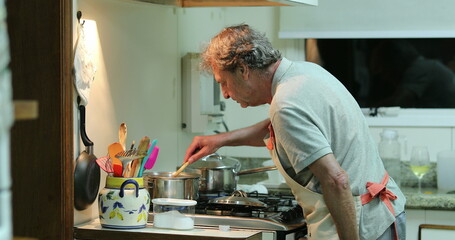 Older senior man cooking at the kitchen, candid chef