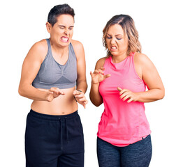 Couple of women wearing sportswear disgusted expression, displeased and fearful doing disgust face because aversion reaction.