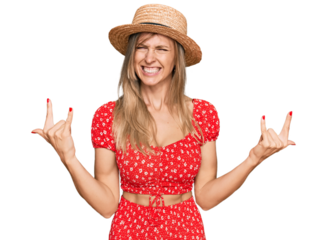 Beautiful caucasian woman wearing summer hat shouting with crazy expression doing rock symbol with hands up. music star. heavy concept.