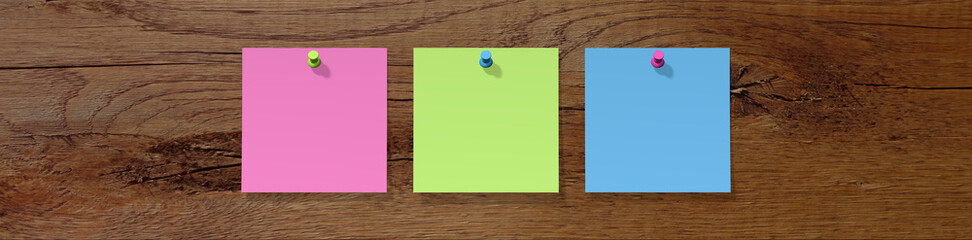 drei bunte Notizzettel an ein Holzbrett gepinnt