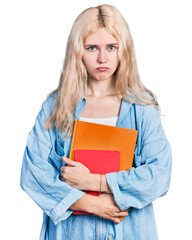 Young caucasian woman holding books depressed and worry for distress, crying angry and afraid. sad expression.