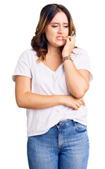 Young beautiful caucasian woman wearing casual white tshirt looking stressed and nervous with hands on mouth biting nails. anxiety problem.