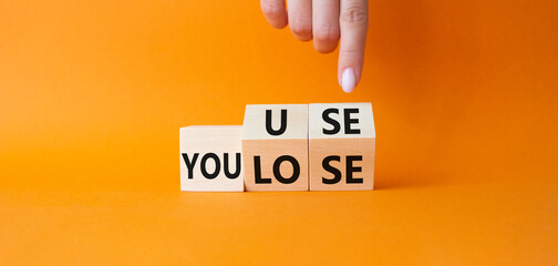 You use or lose symbol. Businessman hand points at cubes with words You lose or You use. Beautiful orange background. Business and You use or lose concept. Copy space