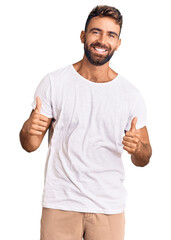 Young hispanic man wearing casual white tshirt success sign doing positive gesture with hand,...