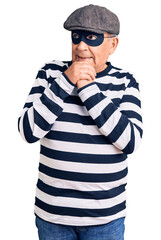 Senior handsome man wearing burglar mask and t-shirt laughing nervous and excited with hands on chin looking to the side