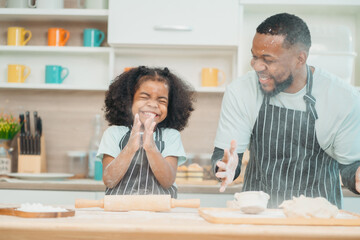 African father enjoy cooking lunch with his daughter, Dad and little girls having a playful while making dinner for the whole family, home cooking, wellbeing activity at home, carefree hobby in family