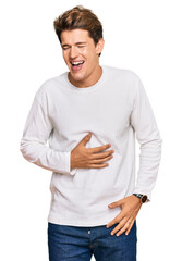 Handsome caucasian man wearing casual white sweater smiling and laughing hard out loud because funny crazy joke with hands on body.