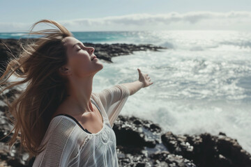 Fototapeta na wymiar Happy brunette woman with open arms and closed eyes on a rocky beach. Concept of freedom