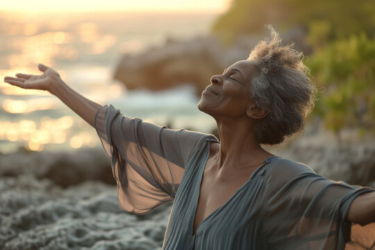 Happy Mature Black Woman With Open Arms And Closed Eyes On A Rocky Beach. Concept Of Freedom