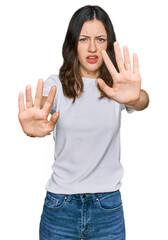 Young beautiful woman wearing casual white t shirt doing stop gesture with hands palms, angry and frustration expression