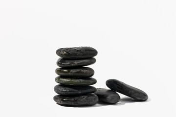 Stacked black spa pebbles on white background