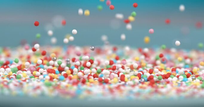 Super slow motion extreme macro of sweet rainbow sugar sprinkles are falling on delicious dessert pink glazed donuts isolated on soft colorful background at 1000 fps.