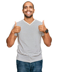 Hispanic adult man wearing casual clothes success sign doing positive gesture with hand, thumbs up smiling and happy. cheerful expression and winner gesture.