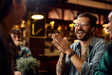 Cheerful man enjoying in conversation with friends in pub.