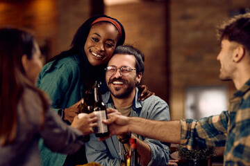 Cheerful friends having fun while gathering in bar and toasting with beer.