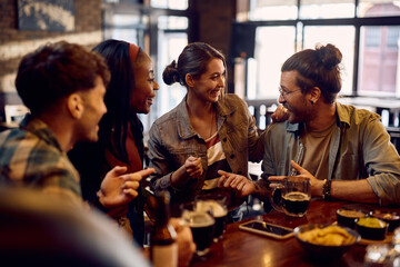 Young happy people communicating while having drink in bar.