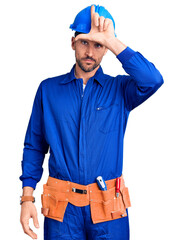 Young handsome man wearing worker uniform and hardhat looking unhappy and angry showing rejection and negative with thumbs down gesture. bad expression.