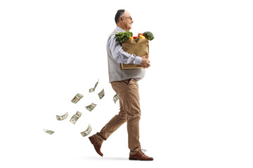 Full length profile shot of a mature man walking with a grocery bag with money falling behind