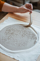 Hand modelling of openwork clay plate, pottery. Women's hands working with clay, close-up - obrazy, fototapety, plakaty