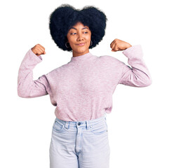 Young african american girl wearing casual clothes showing arms muscles smiling proud. fitness concept.