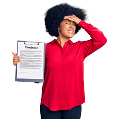 Young african american girl holding clipboard with contract document stressed and frustrated with...