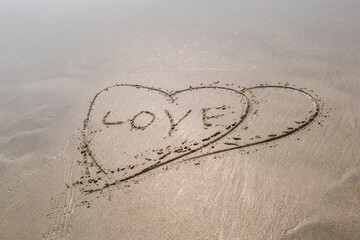 drawing in sand in form of two hearts and inscription love