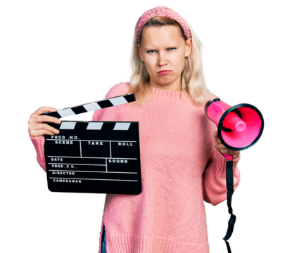Young caucasian woman holding video film clapboard and megaphone skeptic and nervous, frowning upset because of problem. negative person.