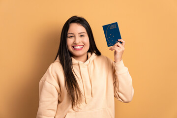 cheerful caucasian woman showing brazilian passport in beige background. travel, trip, brazil...