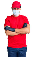 Young hispanic man wearing covid-19 safety mask skeptic and nervous, disapproving expression on face with crossed arms. negative person.