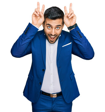 Young hispanic man wearing business jacket posing funny and crazy with fingers on head as bunny ears, smiling cheerful