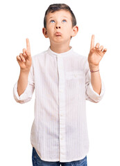 Cute blond kid wearing elegant shirt pointing up looking sad and upset, indicating direction with fingers, unhappy and depressed.