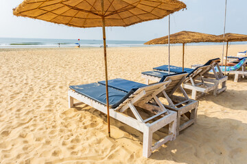 colorful wooden beach umbrellas and sunbeds loungers on sandy beach of ocean