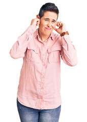 Young woman with short hair wearing casual clothes covering ears with fingers with annoyed expression for the noise of loud music. deaf concept.