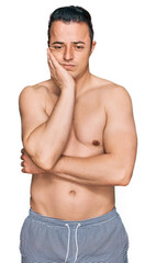 Fototapeta premium Handsome young man wearing swimwear shirtless thinking looking tired and bored with depression problems with crossed arms.