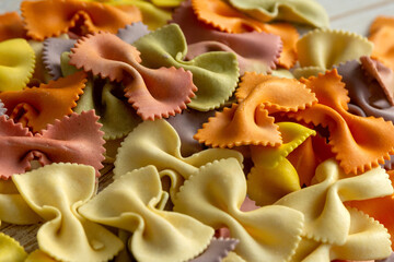 Multi-colored pasta in the shape of a bow tie is laid out on the surface.